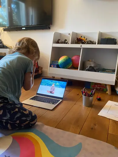 Ein Junge kniet auf der Matte und macht vor dem Laptop mit