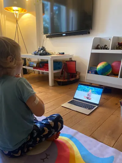 Ein Junge sitzt im Schneidersitz auf der Matte und macht mit Isabell mit