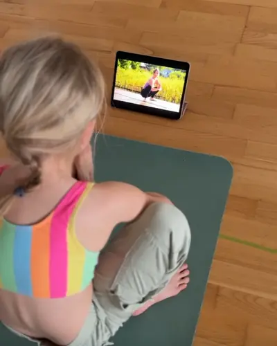 Ein Mädchen sitzt auf der Matte vor dem Tablet