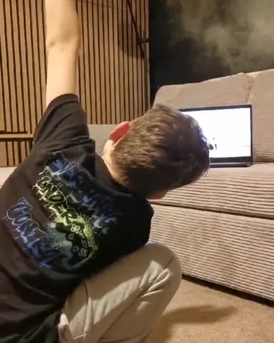 Ein Junge streckt sich vor dem Sofa, auf dem der Laptop steht